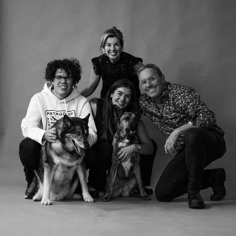 Black-and-white portrait of Gowthorpe and Simard family sitting closely together with two dogs, conveying connection, calm, and support.